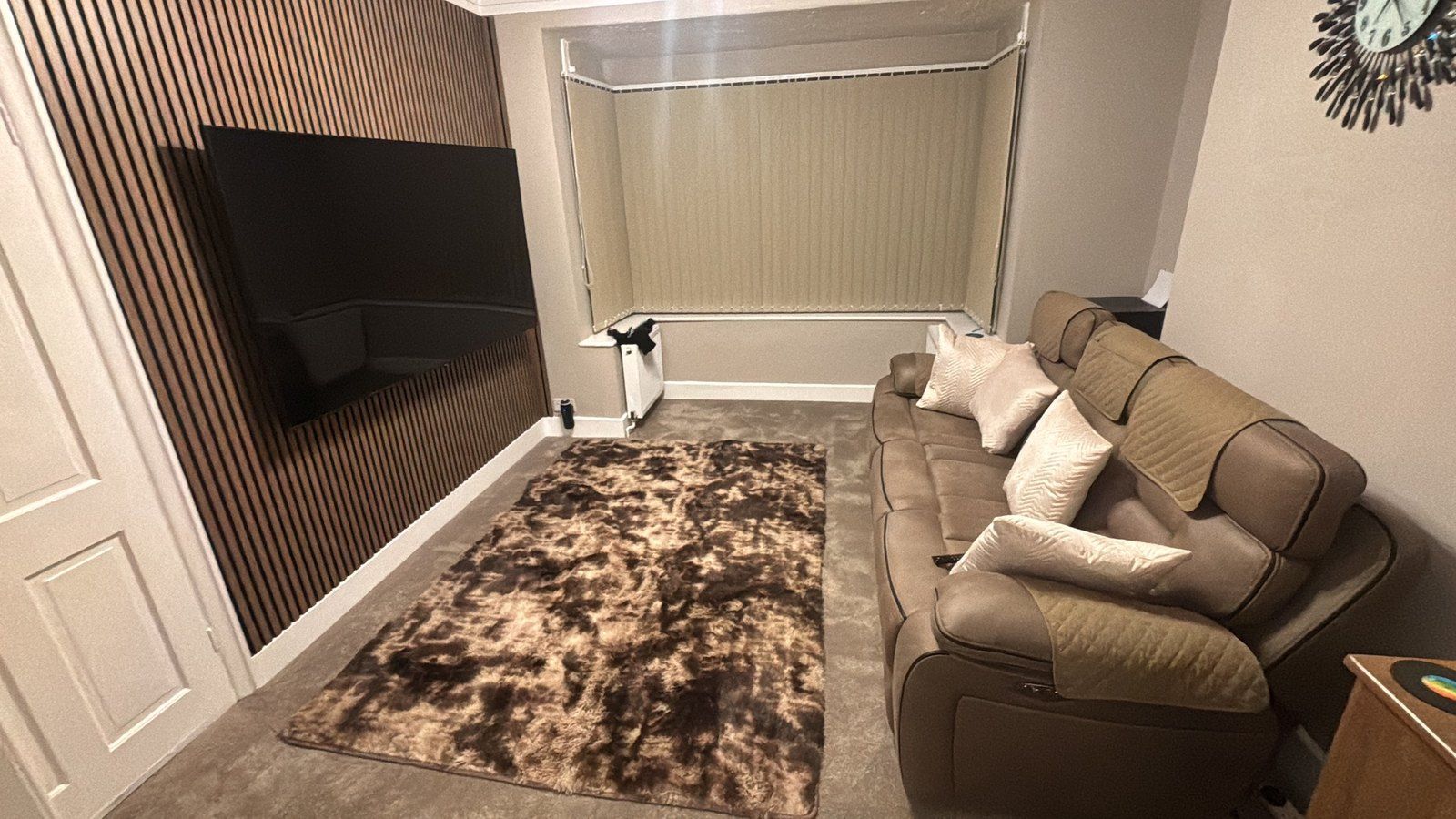 A media room with a slat wall and vertical blinds on the bay window