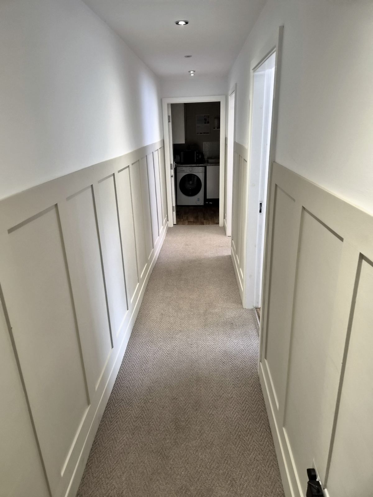 A panelled hallway with grey carpet