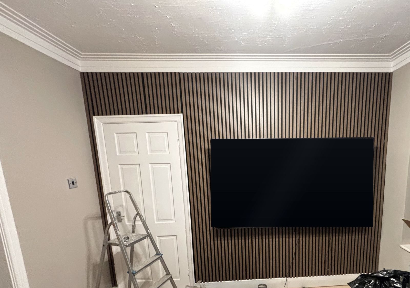 Walnut slat feature wall around a TV